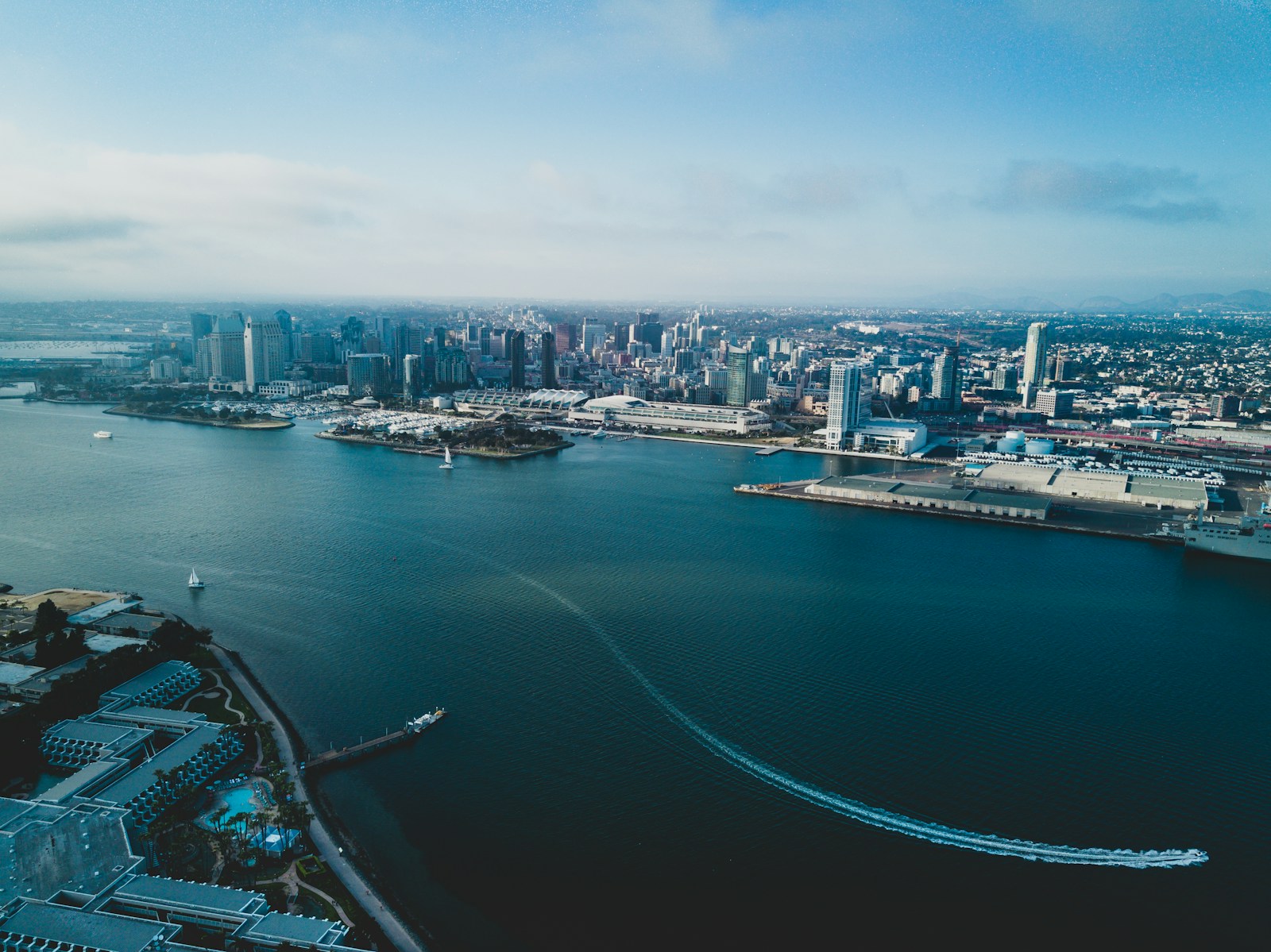 drone view across san diego bay toward downtown towers, the waterfront, and boats on the water